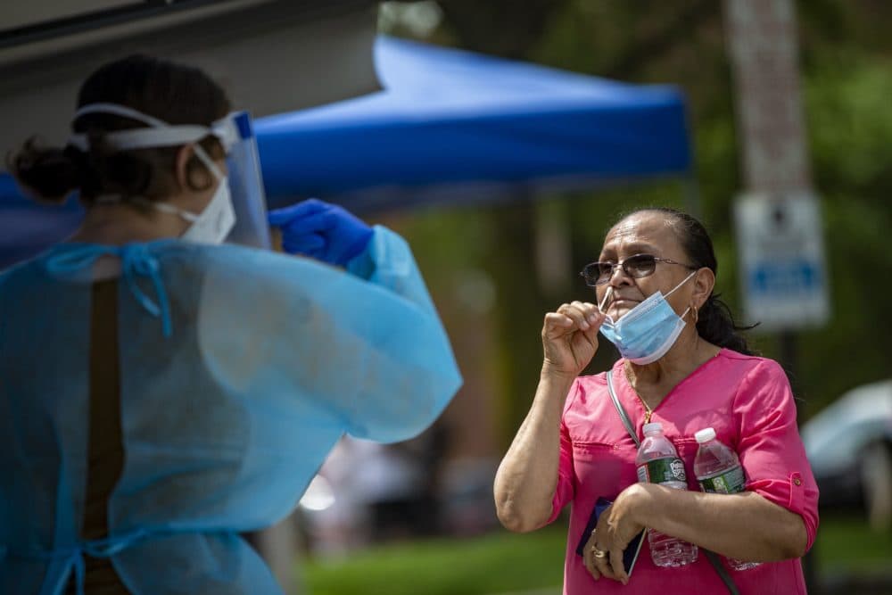 A Chelsea resident is being directed by a health care worker before inserting a swab up her nose during free COVID-19 testing offered by the state in Chelsea Square. (Jesse Costa/WBUR)