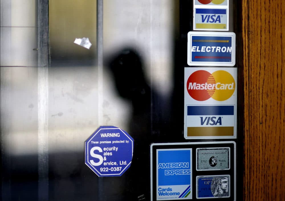 In this 2012 file photo, a pedestrian walks past credit card logos posted on a downtown storefront in Atlanta. (David Goldman/AP)