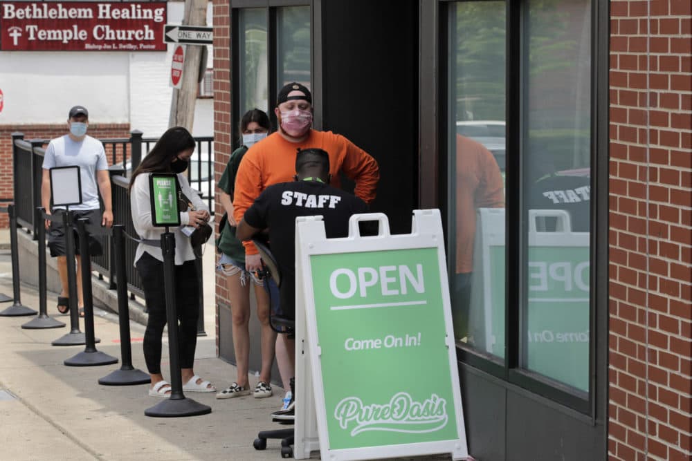 In this June 24, 2020, photograph, customers wait in line at Pure Oasis, a Black-owned recreational marijuana dispensary, in the Grove Hall neighborhood of Boston. Many from outside Boston have recently shopped and supported the store which was robbed and vandalized earlier in the month. (Charles Krupa/AP)