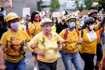 Norma Lewis holds a flower while forming a &quot;wall of moms&quot; during a Black Lives Matter protest on Monday, July 20, 2020, in Portland, Ore. (Noah Berger/AP)