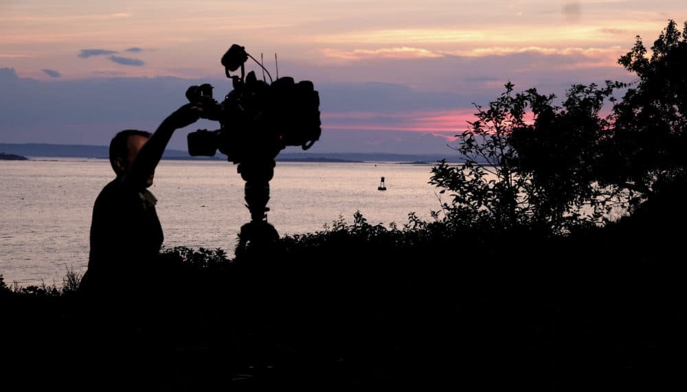 A member of a TV crew adjusts their camera while filming near the shore of Bailey Island, Maine, where a woman swimming off the coast was killed in an apparent shark attack July 27, 2020. Two kayakers helped the person get to shore, and an ambulance provided further assistance, but she was pronounced dead at the scene, Marine Patrol said. (Jim Gerberich/AP)
