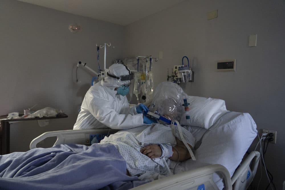 A member of the medical staff treats a patient who is wearing helmet-based ventilator in a COVID-19 intensive care unit in Houston, Texas. (Go Nakamura/Getty Images)