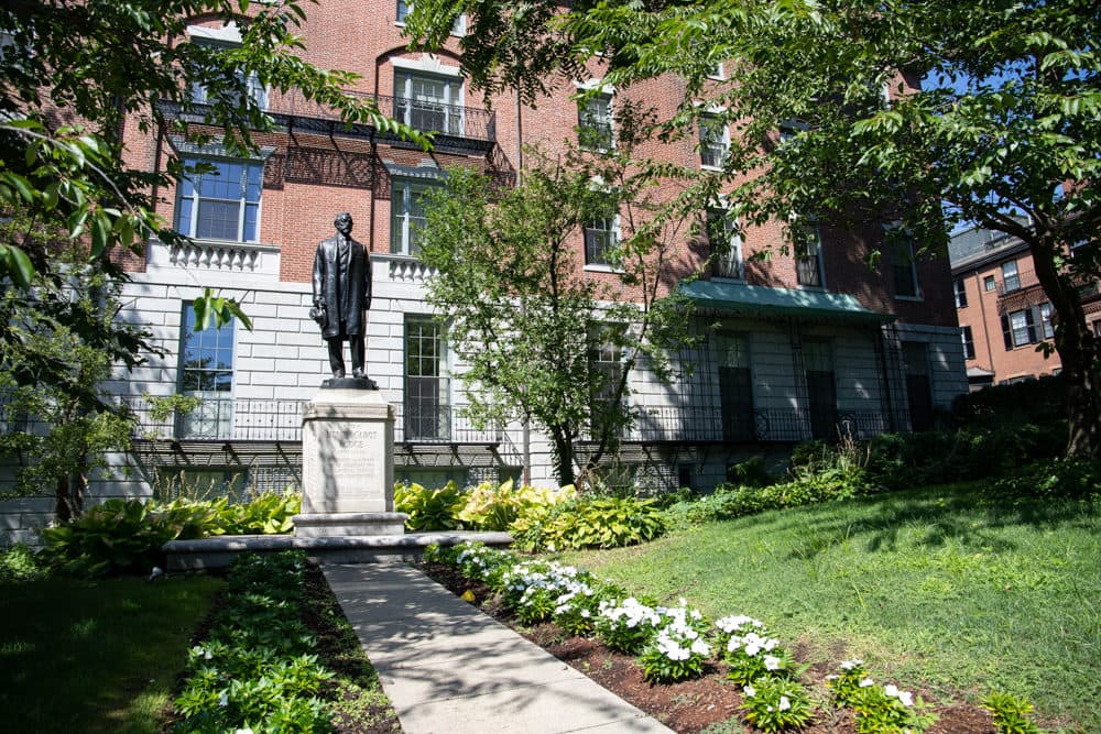 A statue of former U.S. Senate Majority Leader Henry Cabot Lodge stands on the State House west lawn, the site of his now-demolished boyhood home. Rising behind Lodge is 25 Beacon St., former headquarters of the Unitarian Universalist Association. (Sam Doran/SHNS)