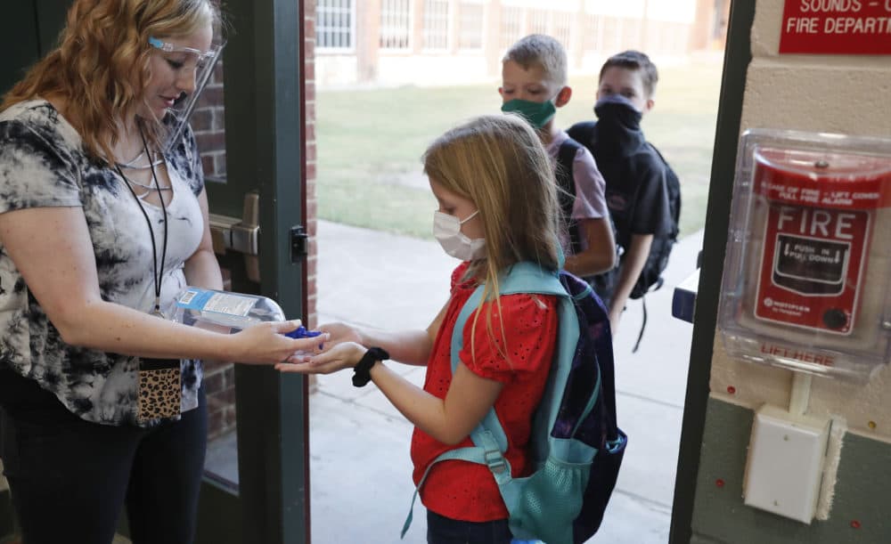 Wearing masks to prevent the spread of COVID19, elementary school students use hand sanitizer before entering school for classes in Godley, Texas on Aug. 5, 2020. (LM Otero/AP)