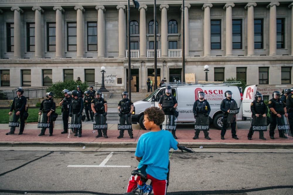 A boy sits on his bike in front of law enforcement at the Kenosha County Courthouse on Aug. 24, 2020 in Kenosha, Wisconsin. (Brandon Bell/Getty Images)