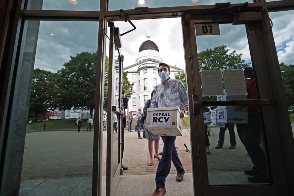 Supporters of an efforts to repeal ranked-choice voting carry boxes of signed petitions into the Cross Building on June 15 in Augusta, Maine. (Robert F. Bukaty/AP)