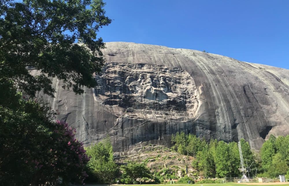 A carving depicting the images of Confederate Generals Stonewall Jackson, Robert E. Lee and Confederate President Jefferson Davis, is engraved on the side of Stone Mountain in Georgia. (Emil Moffatt/WABE)