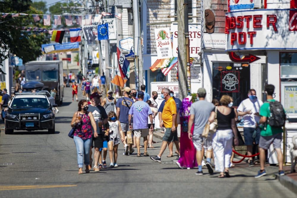 Tourists walk along Commercial Street in Provincetown, an area where local officials ordered it mandatory to wear a mask in the business district due to the coronavirus pandemic. (Jesse Costa/WBUR)