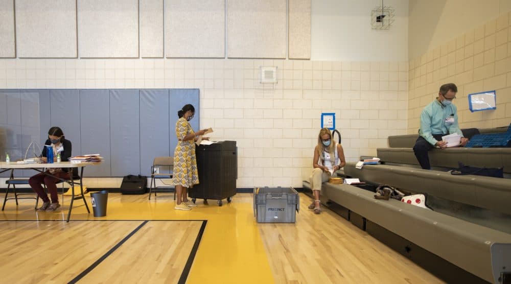 Election workers at the Florida Ruffin Ridley School in Brookline sort through and enter early voting ballots for precinct 3 into a ballot machine. (Jesse Costa/WBUR)