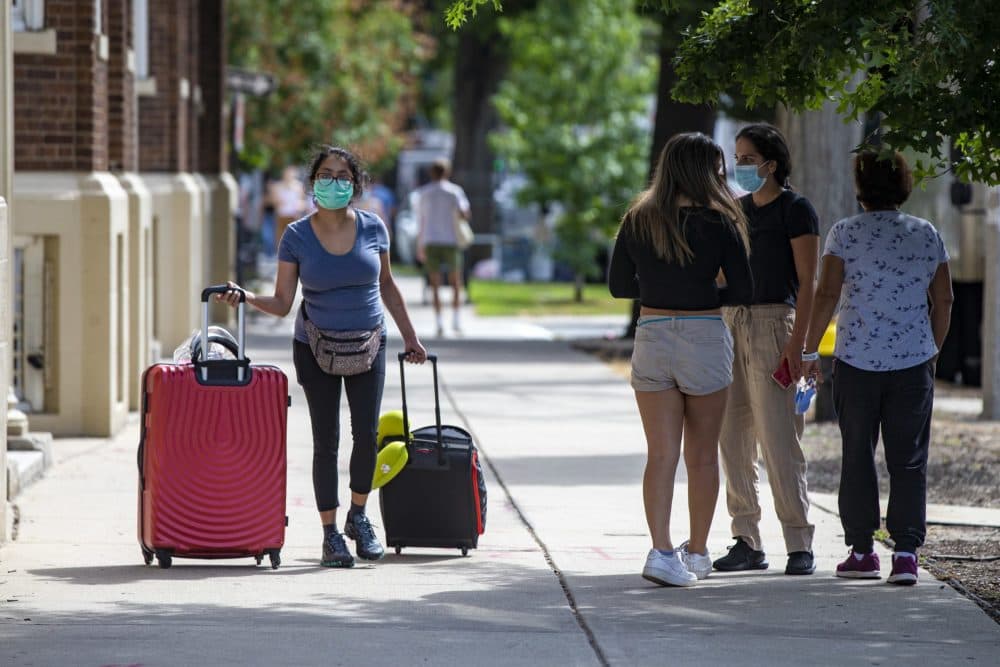 A Boston University student walks along Commonwealth Avenue with her suitcases in tow on Sept. 1. (Jesse Costa/WBUR)