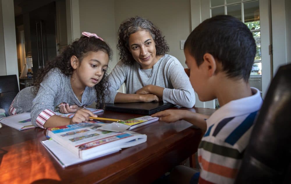 Dr. Maria Diaz, an internist at the Greater Lawrence Family Health Center,  helps her children, Noa, 7, and Ethan, 5, with their schoolwork. (Robin Lubbock/WBUR)