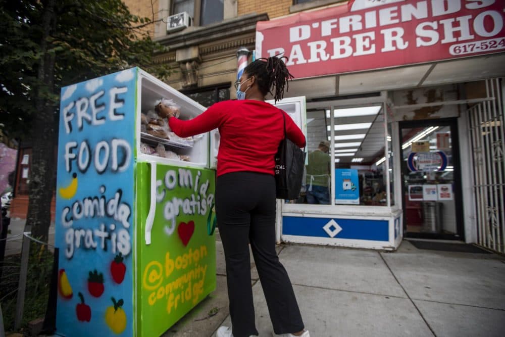 Community fridge volunteer Larissa Williams places baked goods from City Feed into the freezer of the community refrigerator located on Centre Street in Jamaica Plain. (Jesse Costa/WBUR)