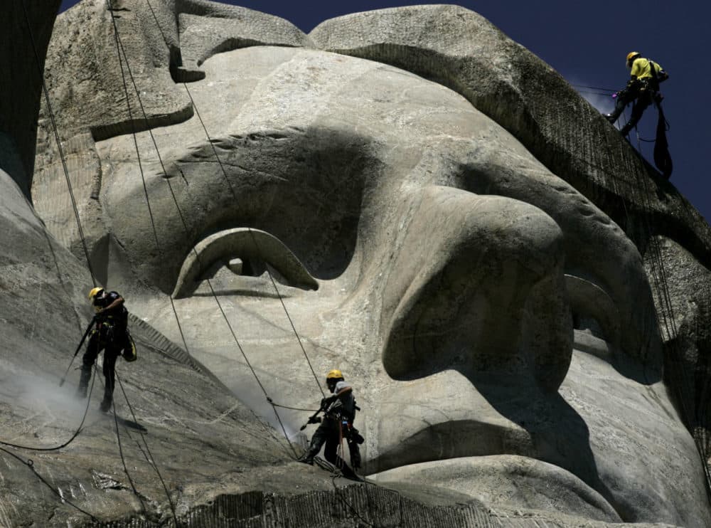 German workers Gerhard Buchar, right, and Winfried Hagenau, left, along with National Park Service employee, Darin Oestman, use pressure washers to clean around the face of Thomas Jefferson at Mount Rushmore National Memorial in South Dakota. (AP Photo/Charlie Riedel, 2005)