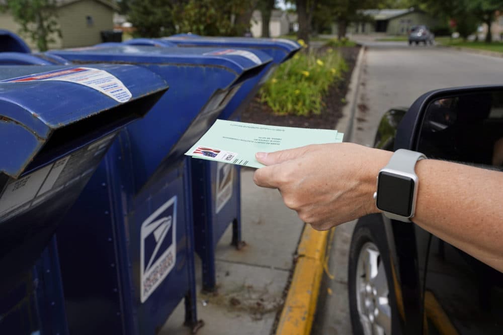 A person drops applications for mail-in-ballots into a mail box in Omaha, Neb. (Nati Harnik/AP)