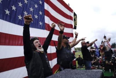 Members of the Proud Boys cheer on stage as they and other right-wing demonstrators rally, Saturday, Sept. 26, 2020, in Portland, Ore. Trump's exchange with Joe Biden Tuesday night left the extremist group Proud Boys celebrating what some of its members saw as tacit approval. (John Locher/AP)