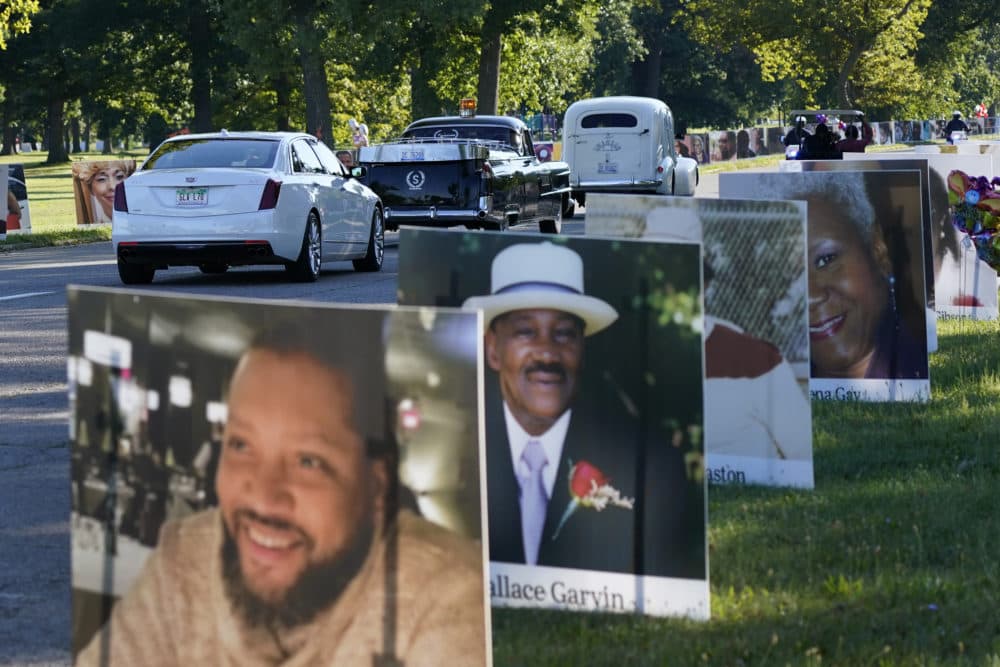 A procession of vehicles drive past photos of Detroit victims of COVID-19 Monday on Belle Isle in Detroit. (Carlos Osorio/AP)