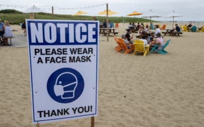 A sign requesting that people wear masks is posted at the Sandbar at Jetties Beach in Nantucket on July 4, 2020. (Photo by Stan Grossfeld/The Boston Globe via Getty Images)