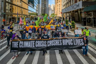 A crowd of climate activists marching behind a banner. A coalition of climate, Indigenous and racial justice groups gathered at Columbus Circle to kick off Climate Week with the Climate Justice Through Racial Justice march, Sept. 20, 2020. (Photo by Erik McGregor/LightRocket via Getty Images)