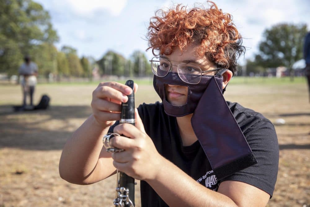 Maxine DeJesus, wearing an adapted mask, gets her clarinet ready at the start of band practice. (Robin Lubbock/WBUR)