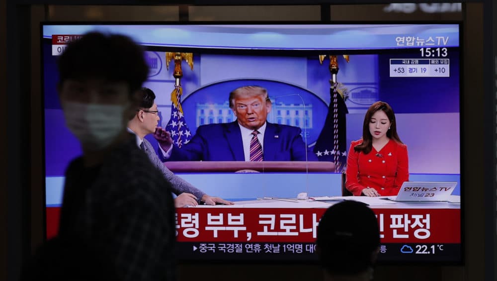 A man wearing a face mask walks near a TV screen reporting about U.S. President Donald Trump and first lady Melania Trump during a news program with a file image of Trump at the Seoul Railway Station in Seoul, South Korea, Friday, Oct. 2, 2020. (Lee Jin-man/AP)