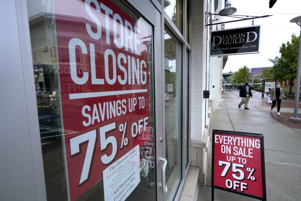 In this Sept. 2, 2020, file photo, passers-by walk past a business storefront with store closing and sale signs in Dedham, Mass. U.S. employers advertised for slightly fewer jobs in August while their hiring ticked up modestly. The Labor Department said Tuesday that the number of U.S. job postings on the last day of August dipped to 6.49 million, down from 6.70 million July. (Steven Senne/AP File)