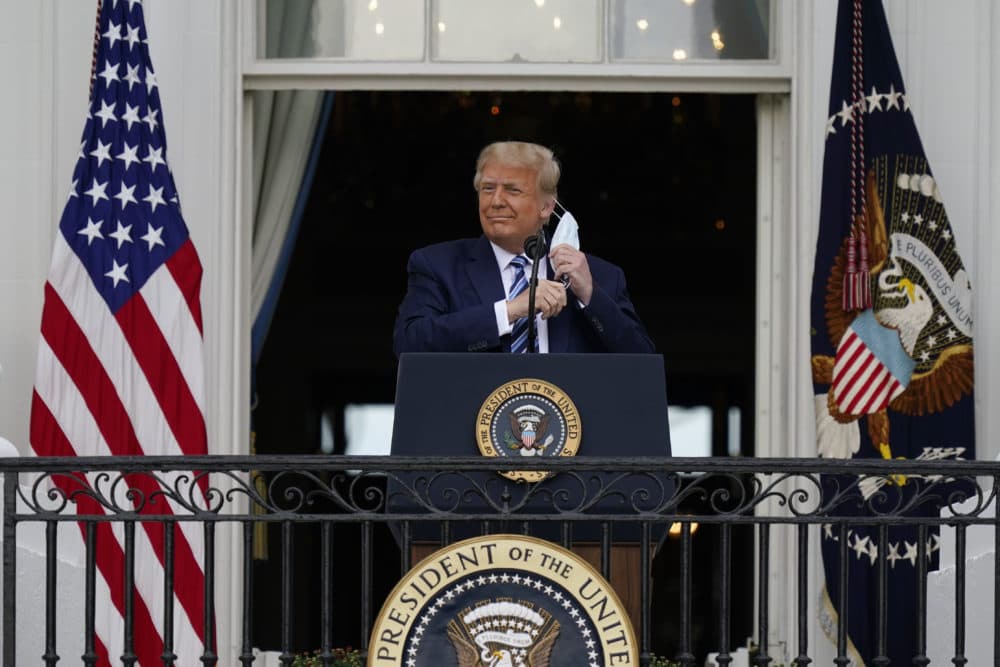 President Donald Trump removes his face mask to speak from the Blue Room Balcony of the White House to a crowd of supporters, Saturday, Oct. 10, 2020, in Washington. (Alex Brandon/AP)