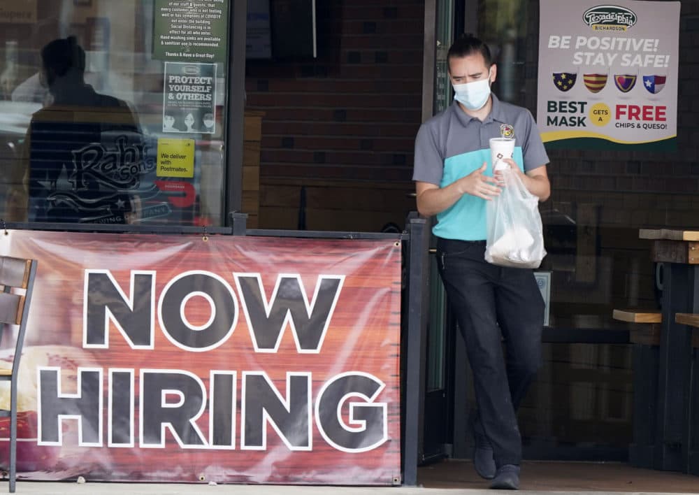 In this Sept. 2, 2020 photo, a customer wears a face mask as they carry their order past a now hiring sign at an eatery in Richardson, Texas. The number of Americans seeking unemployment benefits fell last week to 751,000, the lowest since March, but it's still historically high and indicates the viral pandemic is still forcing many employers to cut jobs. (LM Otero/AP File)