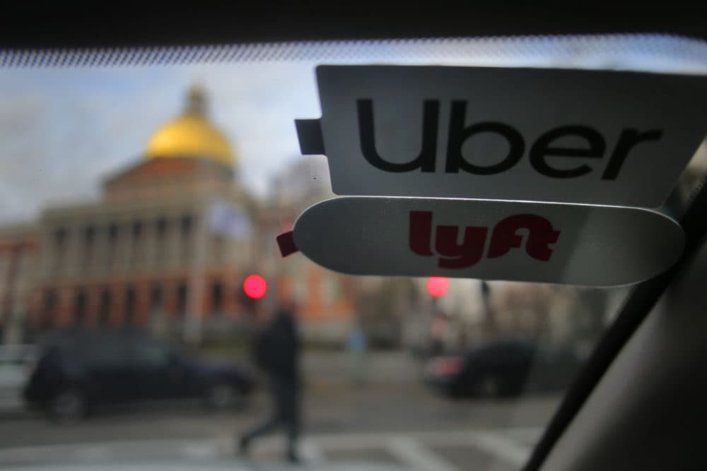 Uber and Lyft stickers are pictured inside a ride-hailing vehicle outside the Massachusetts State House in Boston on Nov. 14, 2019. (Lane Turner/The Boston Globe via Getty Images)