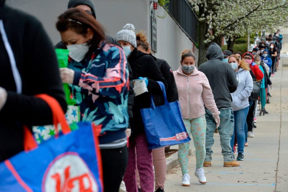 Hundreds of people line up to receive food and goods distributed by volunteers from the Chelsea Collaborative Inc. outside the Pan Y Cafe in Chelsea on April 14, 2020. (Joseph Prezioso/ AFP via Getty Images)