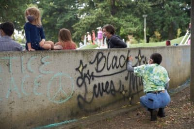 Julia Mapilisan spray paints &quot;Black Lives Matter&quot; on a wall as people gather at Lents Park in Portland, Oregon, on September 5, 2020, to mark the 100th day of protests denouncing police brutality and racism. (Allison Dinner/AFP via Getty Images)