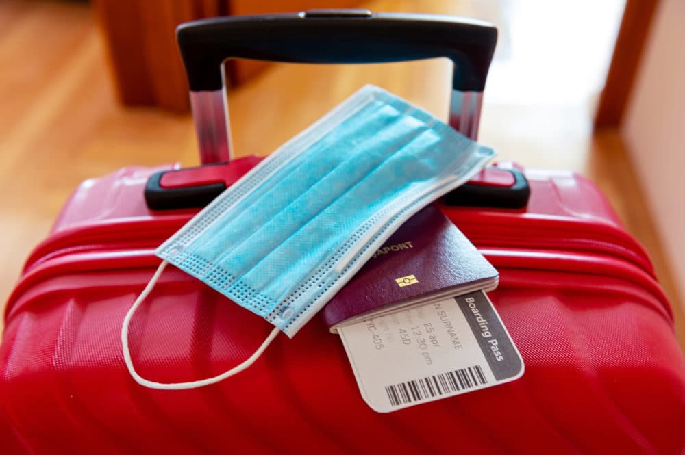Face protection mask and travel documents over trolley bag. Travel and flight rules during coronavirus pandemic crisis. (Getty Images)