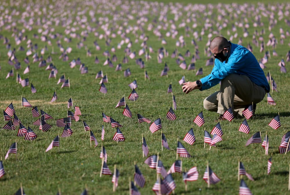 Chris Duncan, whose 75 year old mother Constance died from COVID on her birthday, photographs a COVID Memorial Project installation of 20,000 American flags on the National Mall as the United States crosses the 200,000 lives lost in the COVID-19 pandemic. (White House. (Photo by Win McNamee/Getty Images)