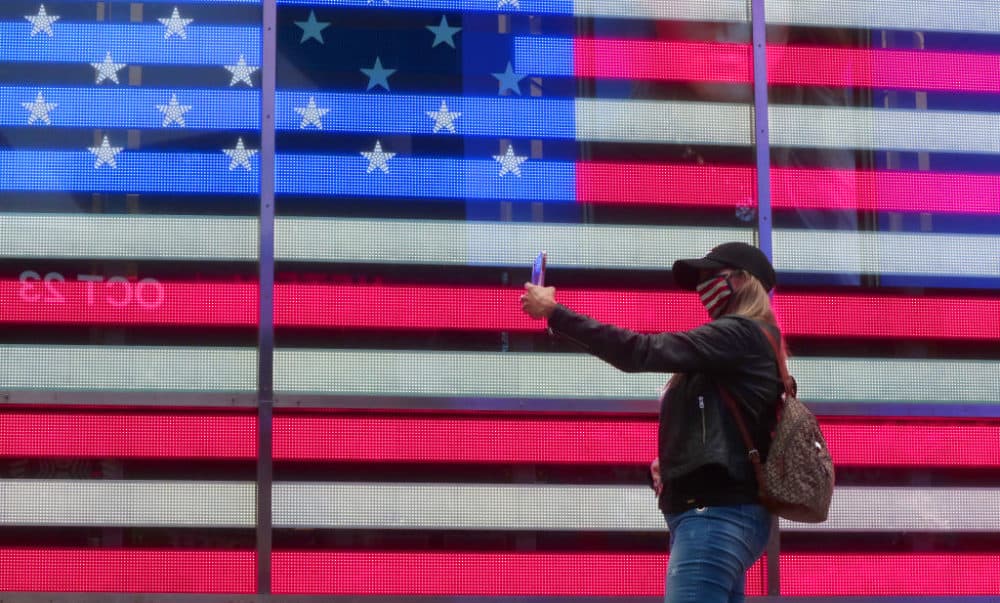 A person in a mask takes a selfie in front of the American flag on October 22, 2020, in New York City. (Gary Hershorn/Getty Images)