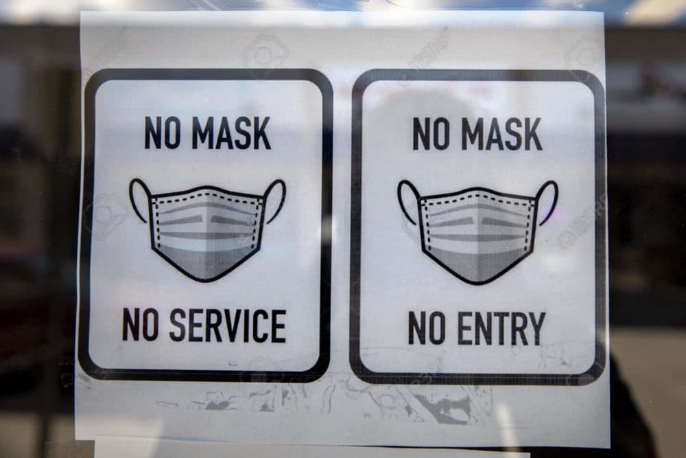 Mask policy on the door at Cash Point in Medford Square. (Robin Lubbock/WBUR)