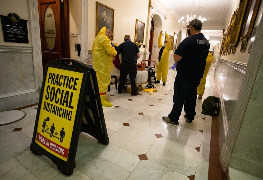 Staff members from Clean Harbors, a company that offers COVID-19 decontamination and disposal services, pulled on yellow jumpsuits before entering the House speaker's office. (Sam Doran/SHNS)