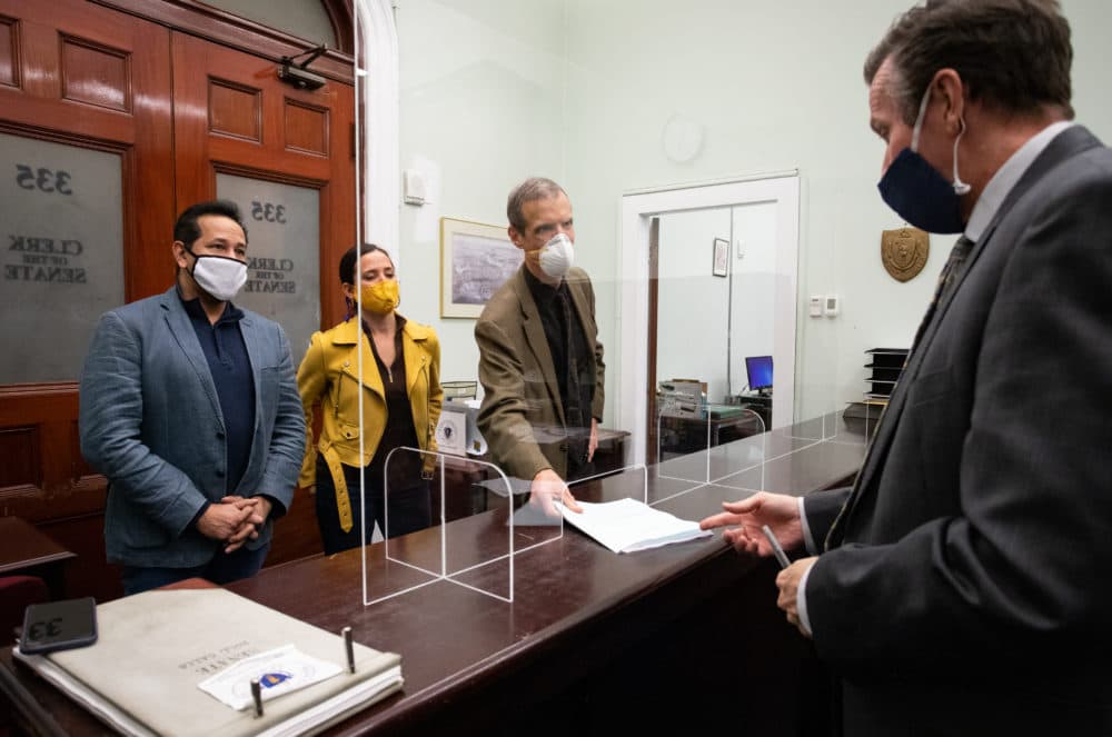 Rep. Carlos Gonzalez, Sen. Sonia Chang-Diaz, and Sen. Will Brownsberger deliver their committee's compromise policing reform bill to Senate Clerk Michael Hurley. [Sam Doran/SHNS]