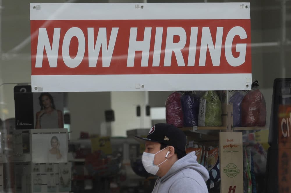 This May 7, 2020, file photo shows a man wearing a mask while walking under a Now Hiring sign at a CVS Pharmacy during the coronavirus outbreak in San Francisco.(Jeff Chiu/AP File)