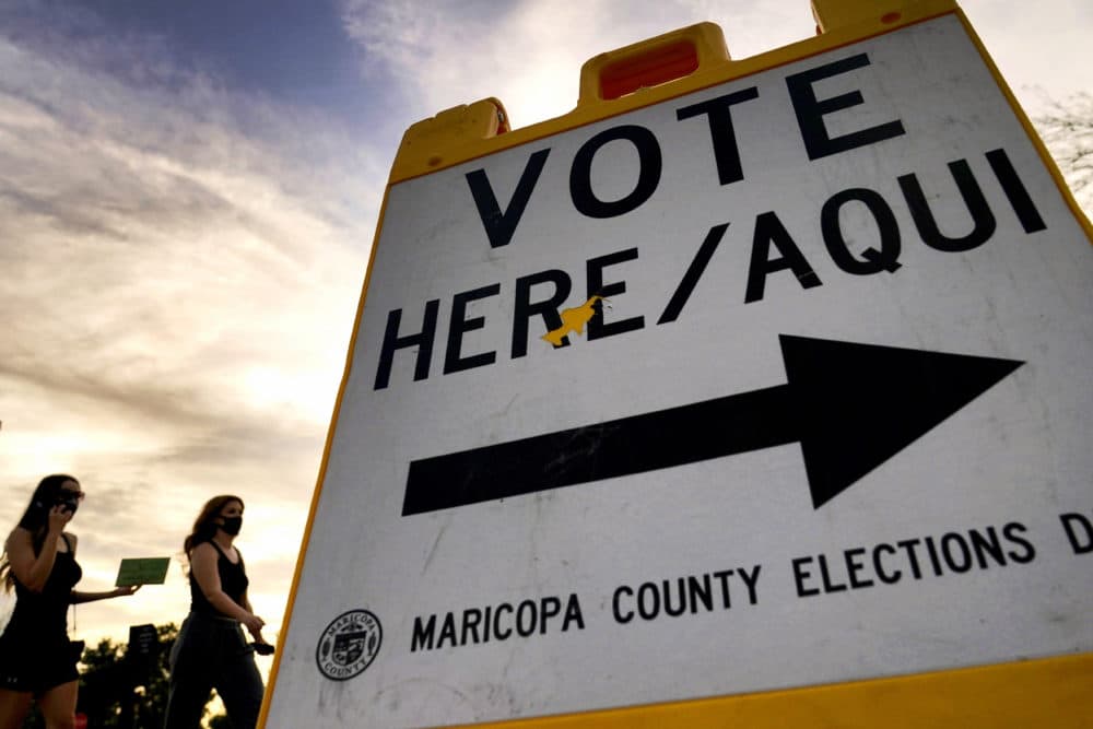 Voters deliver their ballot to a polling station, Tuesday, Nov. 3, 2020, in Tempe, Ariz. (AP Photo/Matt York)