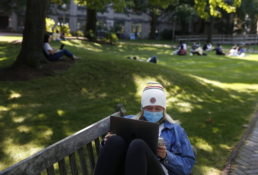 A student works on her laptop outside at Boston University on Sept. 23, 2020. This year, Gov. Charlie Baker is asking colleges to test students before and after any Thanksgiving travel. (Jessica Rinaldi/The Boston Globe via Getty Images)