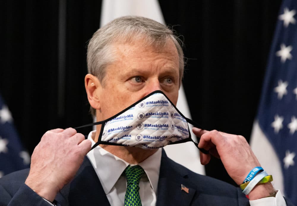 Gov. Charlie Baker puts on a mask after announcing new restrictions on businesses during the fall coronavirus surge (Sam Doran/SHNS)