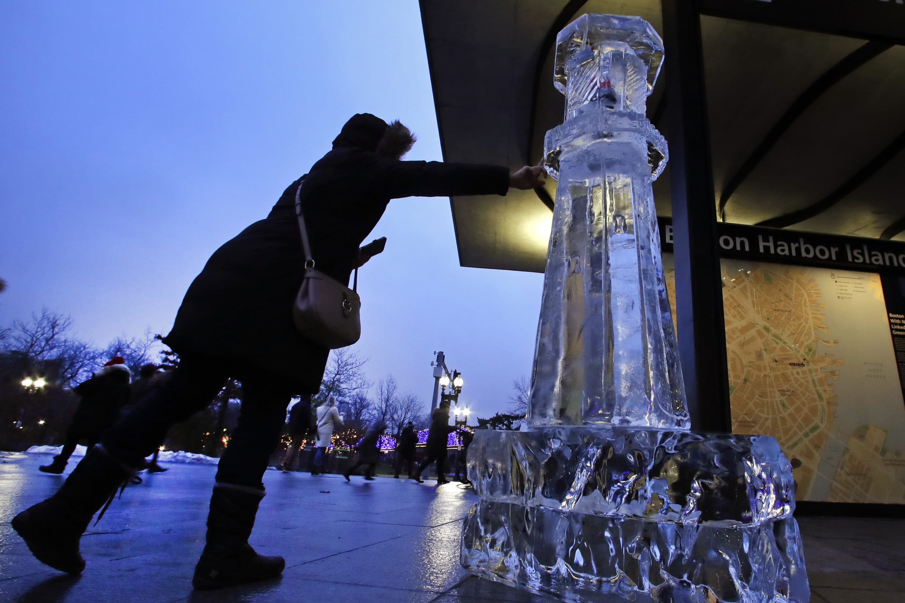 A woman reaches to touch a lighthouse ice sculpture, Friday, Dec. 31, 2019, in Boston. Ice sculptures make a return to the Boston Harborwalk for the 2020 First Night celebration. (AP Photo/Elise Amendola)