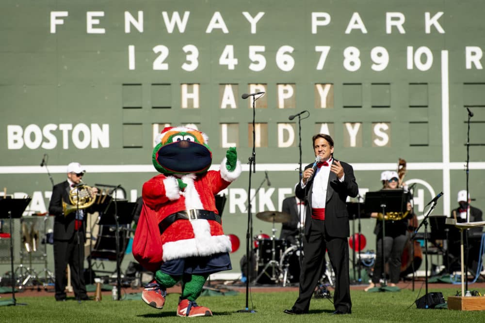 Red Sox mascot Wally the Green Monster makes a cameo appearance for “Must Be Santa” while Lockhart and the orchestra members sing along. (Courtesy Maddie Malhotra/Boston Red Sox)