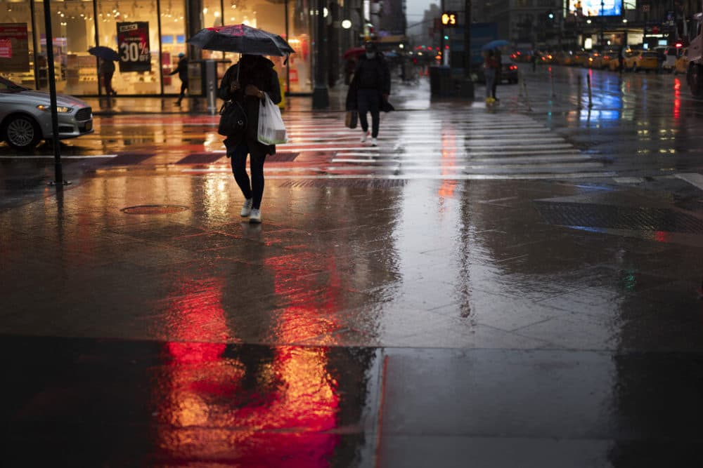 A shopper walks in a rainstorm, Nov. 30, 2020 in New York. (Mark Lennihan/AP)