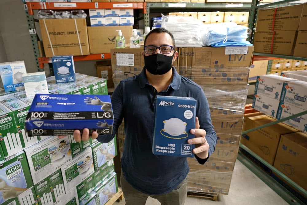 Ray Bellia holds up personal protective masks and gloves, used by medical and law enforcement professionals, in the warehouse of his Body Armor Outlet store, Wednesday, Dec. 9, 2020, in Salem, N.H. (Charles Krupa/AP)