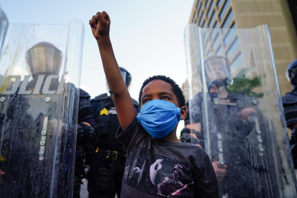 A young boy raises his fist for a photo by a family friend during a demonstration on May 31, 2020 in Atlanta, Georgia. (Elijah Nouvelage/Getty Images)