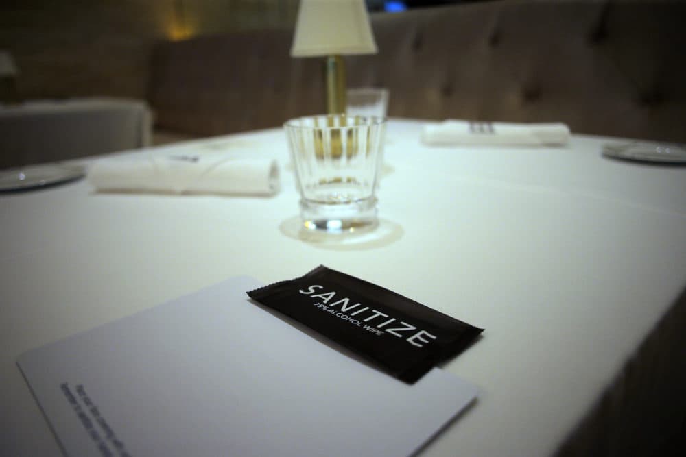 Tables in a restaurant with sanitizer, a mat for masks and wrapped utensils at The Encore Boston Harbor Casino in Everett on July 9, 2020. (Photo by Lane Turner/The Boston Globe via Getty Images)