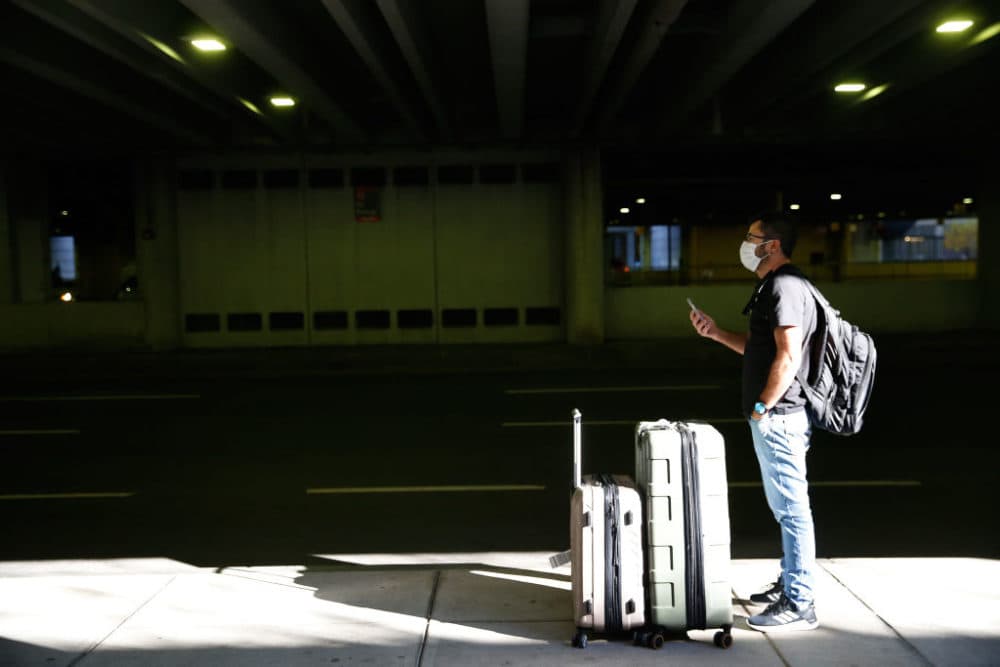 A man waits for his ride outside of Logan International Airport in Boston on Nov. 29, 2020, following the Thanksgiving holiday. Travel is expected to rebound to near pre-pandemic levels this Thanksgiving. (Jessica Rinaldi/The Boston Globe via Getty Images)