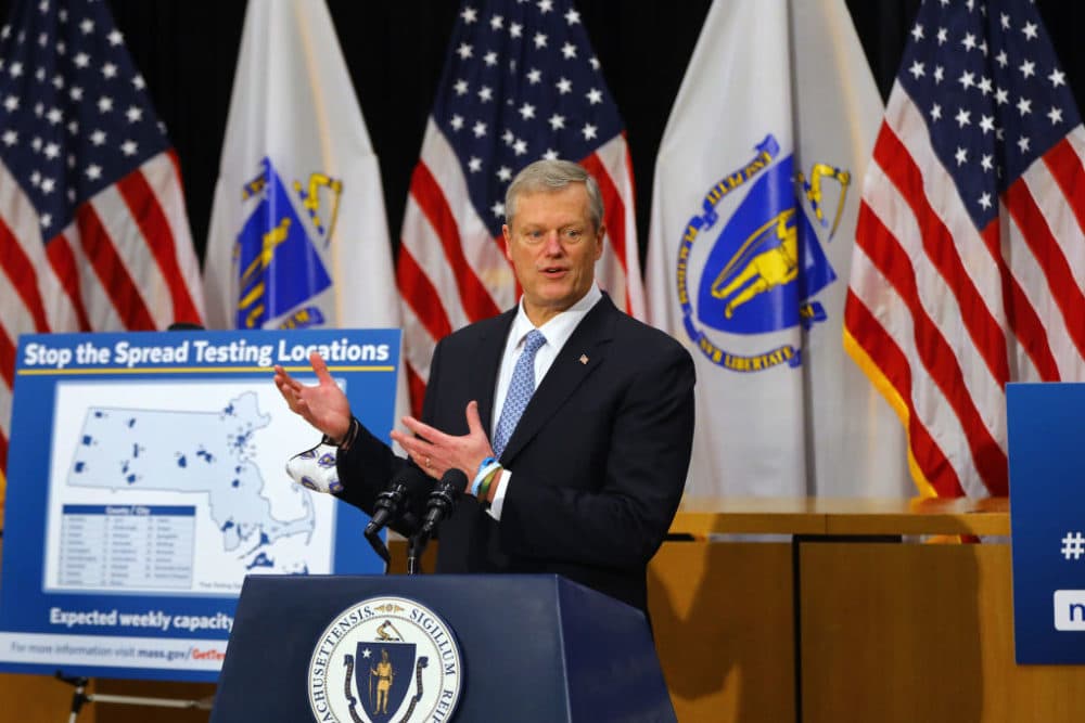 Gov. Charlie Baker stands next to a sign reading &quot;Stop the Spread Testing Locations&quot; as he speaks during a press conference in the Gardner Auditorium in the State House on Dec. 7. (Pat Greenhouse/The Boston Globe via Getty Images)