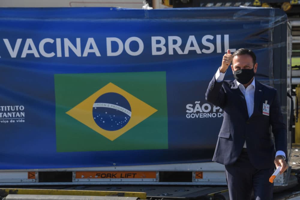 Sao Paulo Gov. Joao Doria gives the thumb up as he poses for photos holding a dose of the CoronaVac vaccine against COVID-19 next to a container unloaded from a cargo plane that arrived from China on December 18, 2020. (Nelson Almeida/AFP/Getty Images)