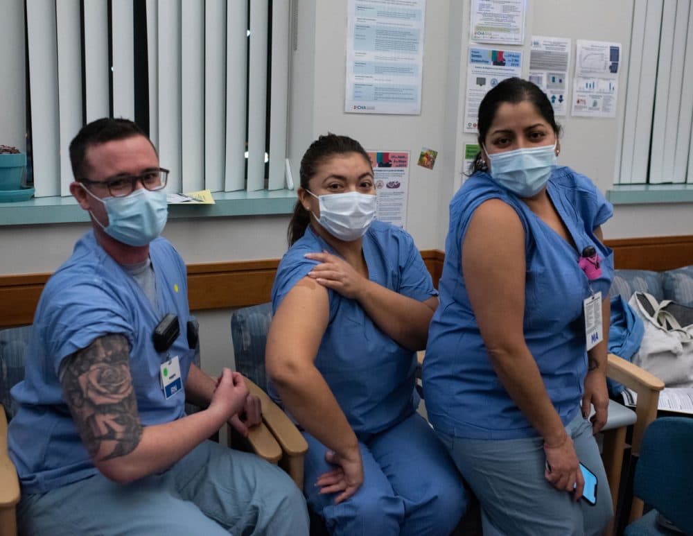 Staffers at the Cambridge Health Alliance clinic for COVID-19 patients in Somerville -- RN Erik Westhaver and Medical Assistants Nancy Morales and Carla Ayala -- show off their newly vaccinated arms. (Courtesy Dr. Anna Rabkina, Cambridge Health Alliance)